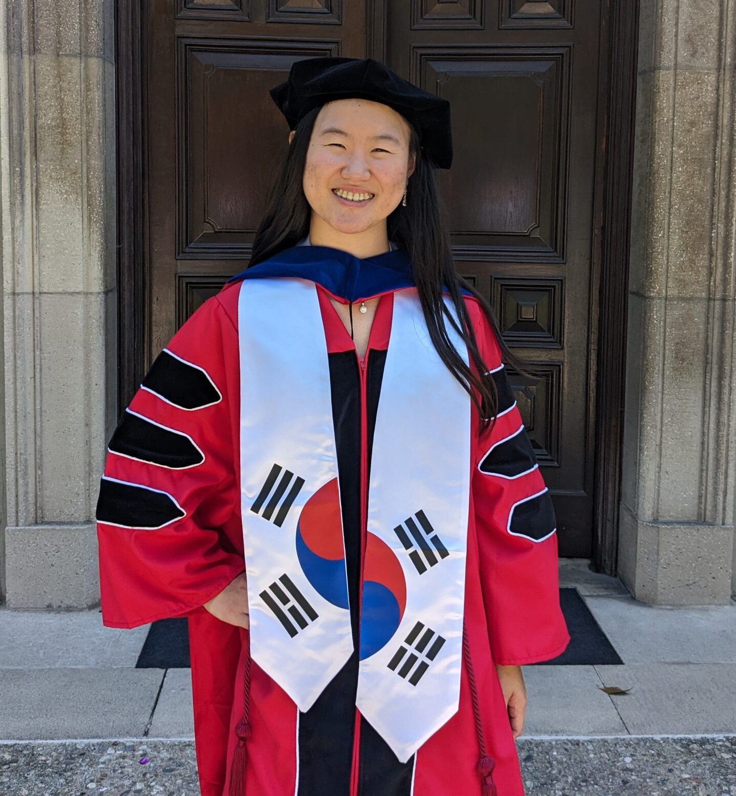 woman with long black hair wearing doctoral regalia